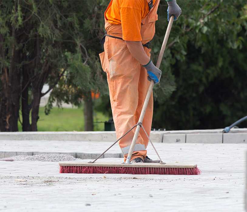 Man in construction suit brushing concrete debris with a broom